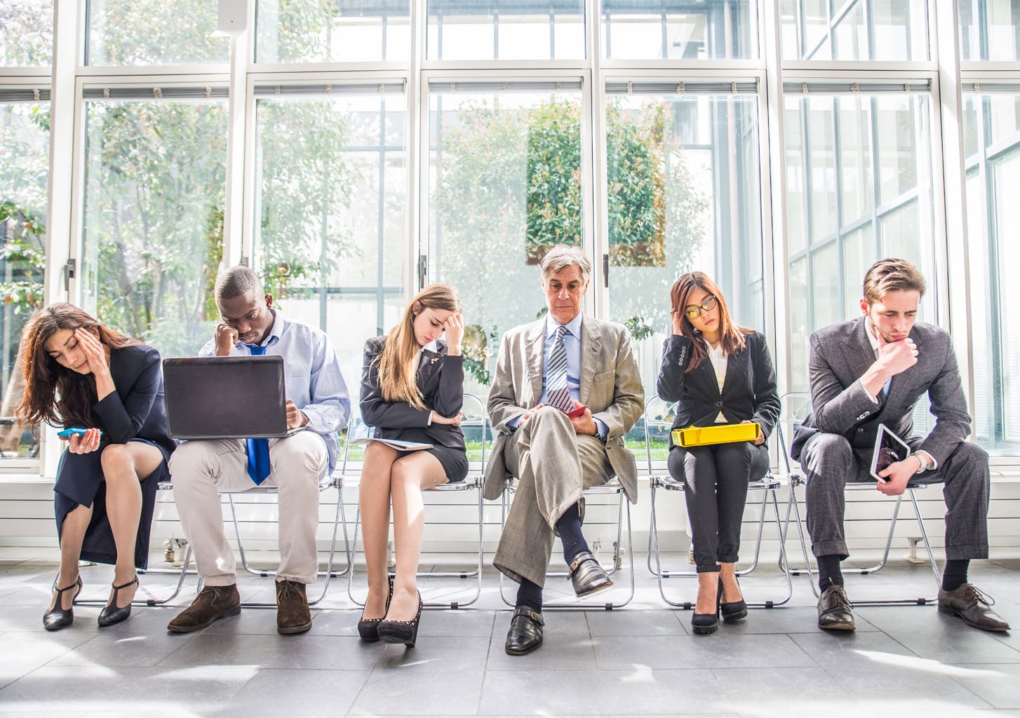 A row of candidates waiting in an office lobby before interviews