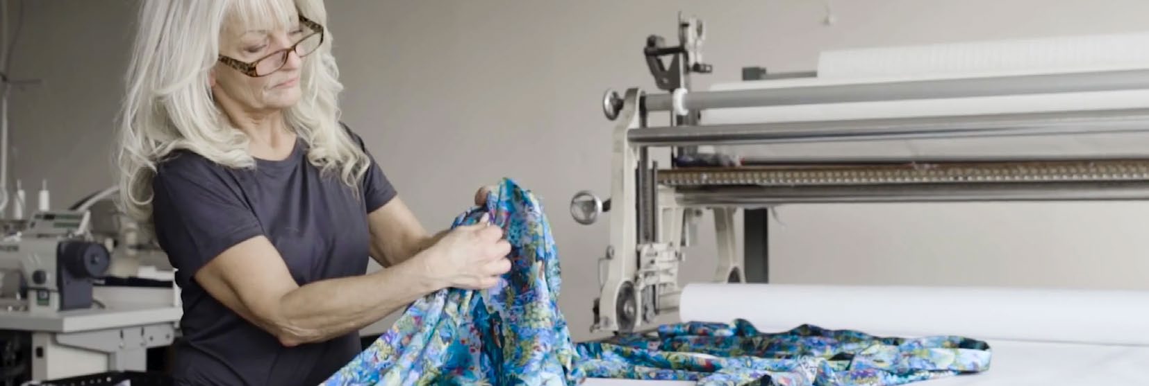 A woman laying out patterned fabric at a cutting machine in the Derek Rose workshop