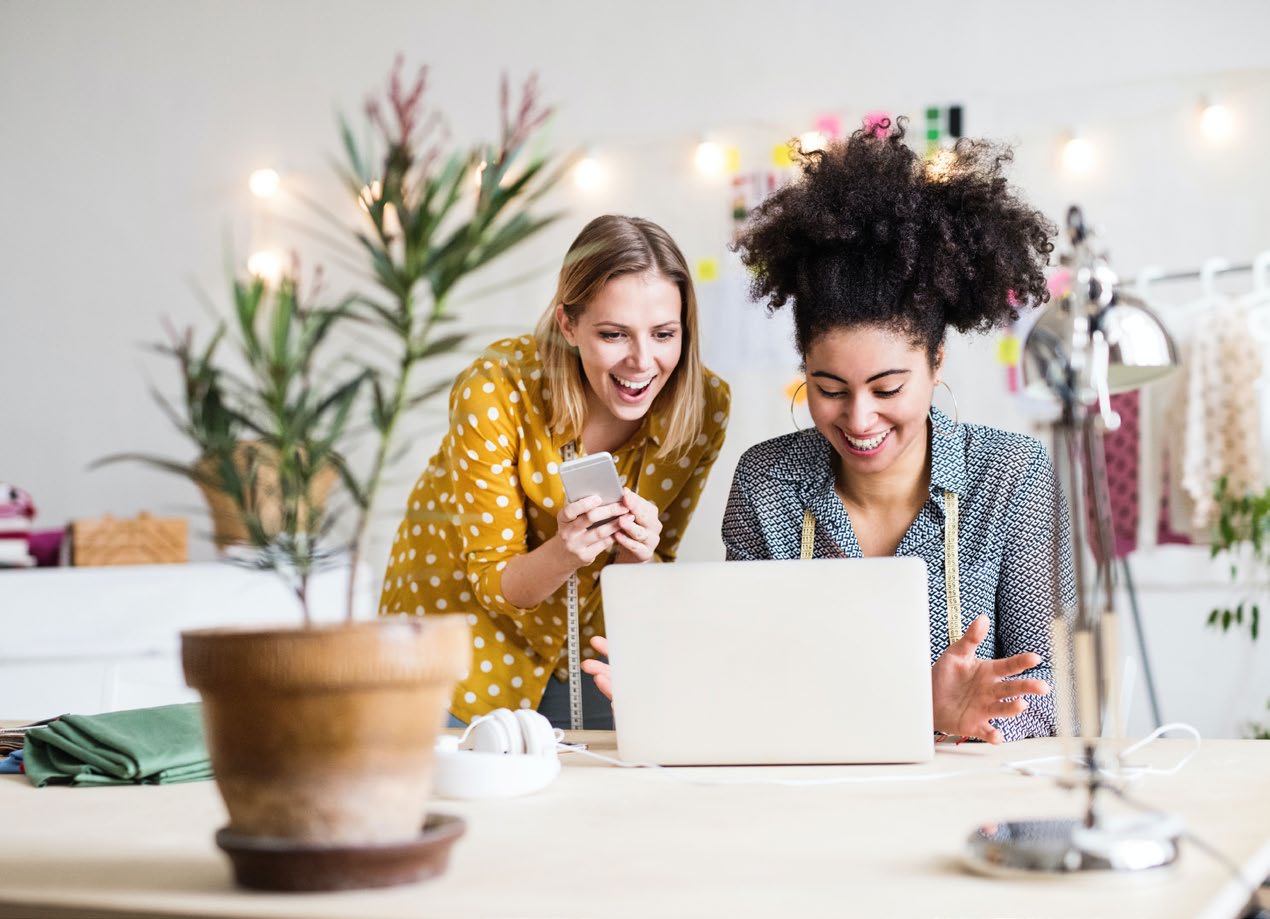 Two colleagues looking at a laptop together and smiling