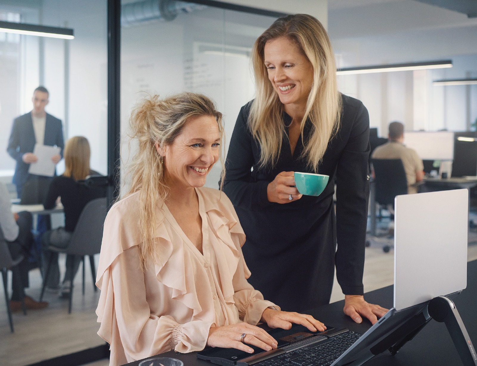 Two colleagues looking at a screen together in a bright open-plan office