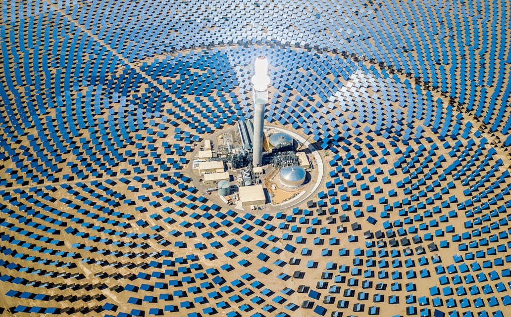 Aerial view of a concentrated solar power plant, thousands of mirrors arranged around a central tower