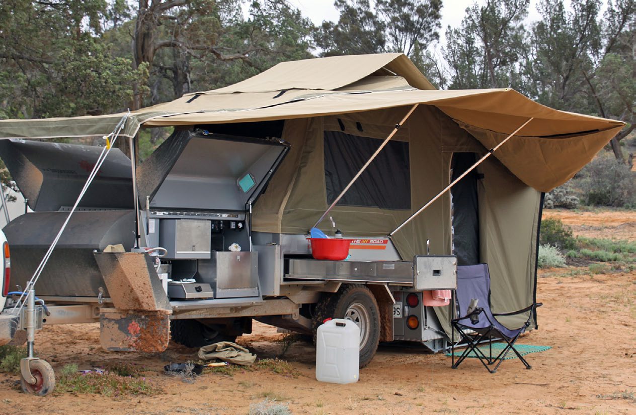 A hard-floor Kimberley camper trailer set up with its canvas extended and slide-out kitchen open