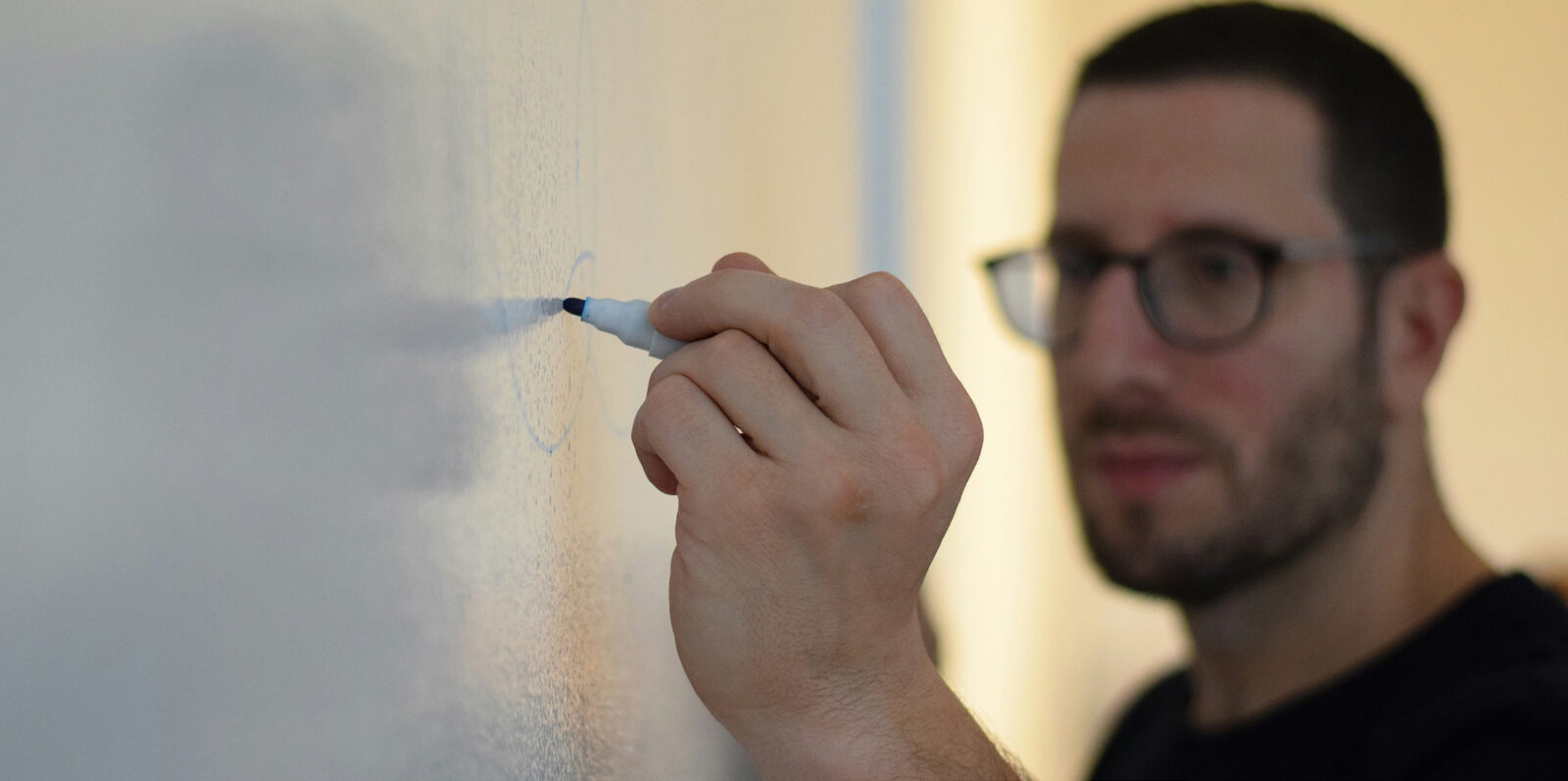 An instructor writing on a whiteboard during a classroom session
