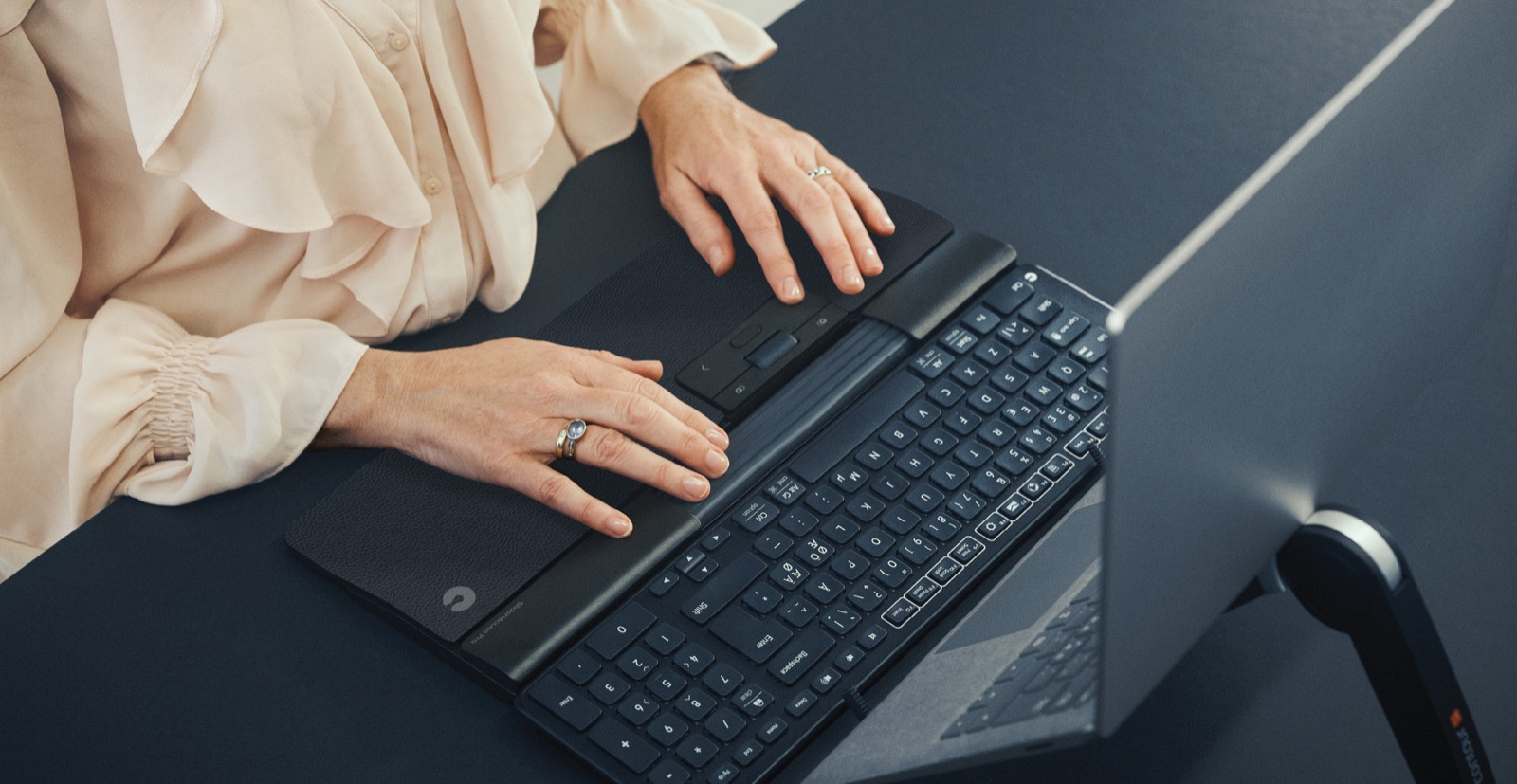 Hands resting on an ergonomic keyboard and rollerbar