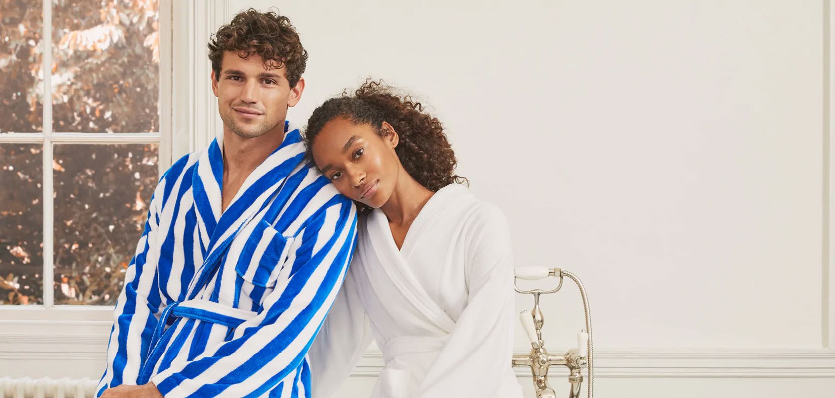 Two people wearing Derek Rose dressing gowns in a bright bathroom