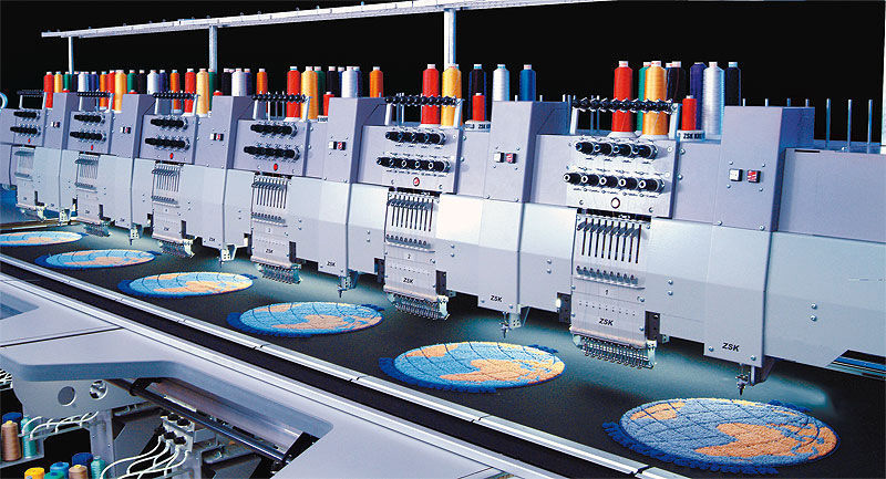 A line of multi-head industrial embroidery machines on a factory floor